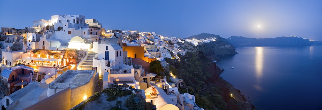 Rooftops of houses and villas on rim of caldera at dusk.